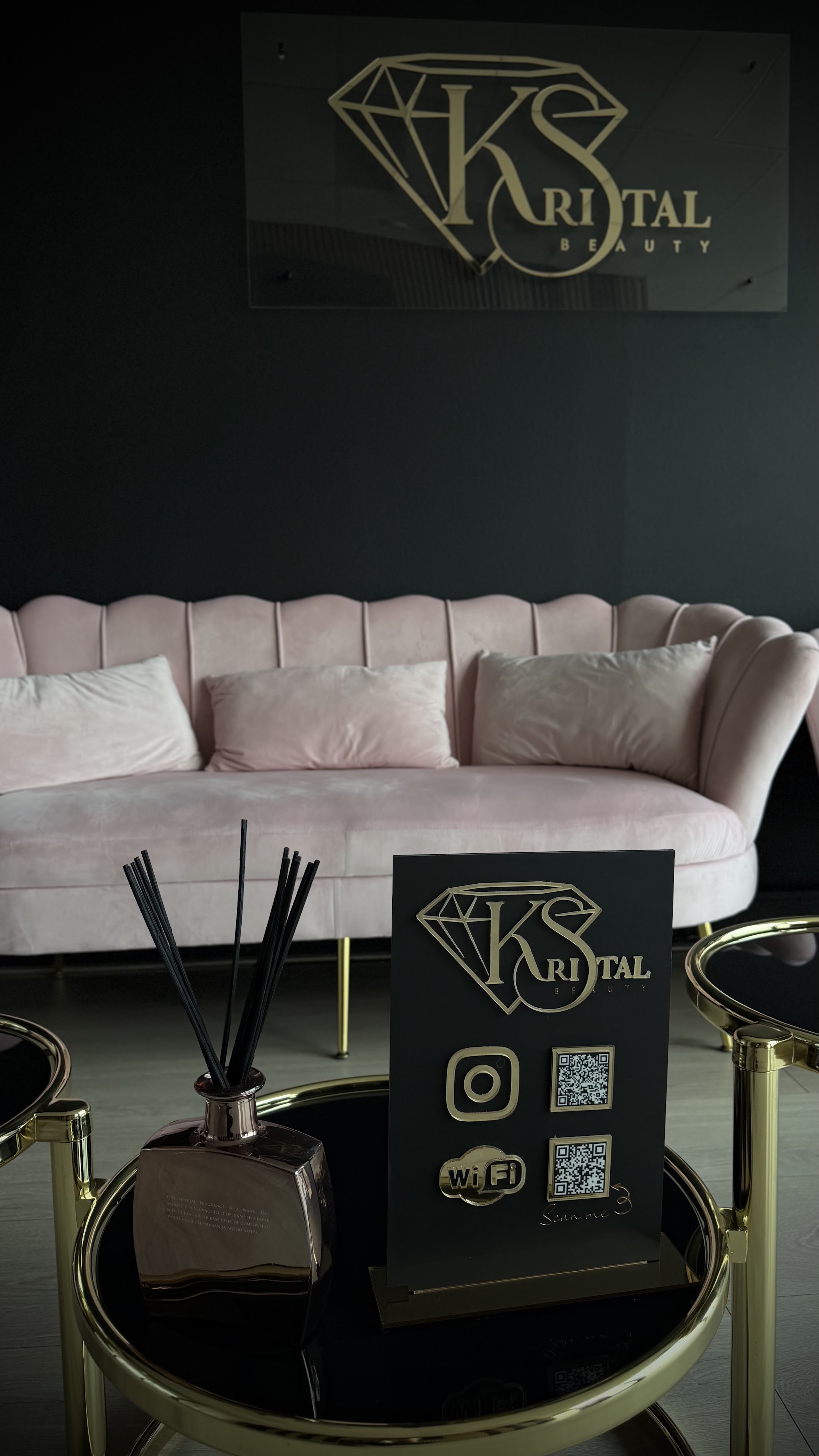 De roze schelpsofa met geurstokjes en een staand bordje met het Kristal Beauty-logo, Instagram, QR-code en wifi