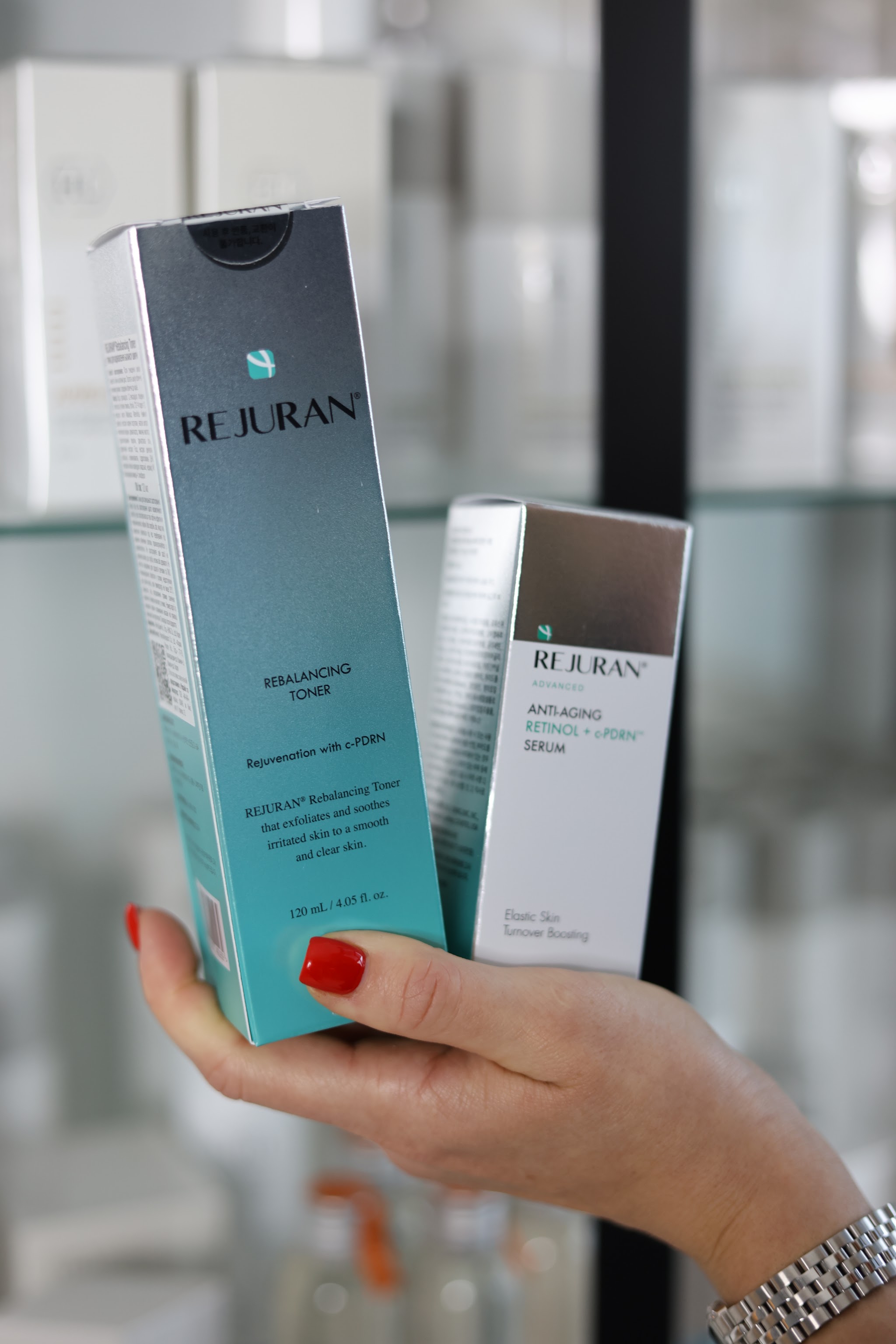 Twee Rejuran-verpakkingen, een toner en een retinolserum, in de hand
